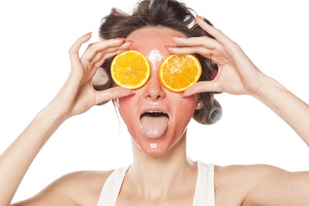 70218769 - young woman with a mask holding a piece of orange on the eyes