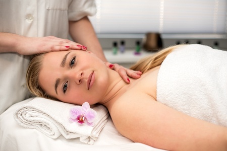 53690060 - young woman lying on massage table receiving face massage. beauty treatment concept.